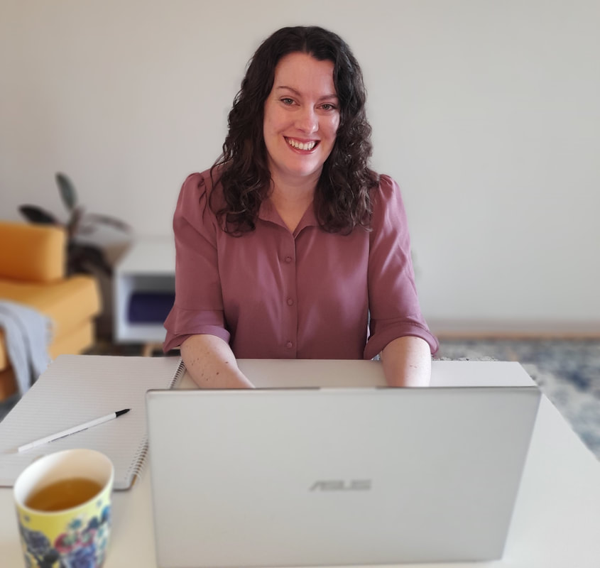 Ballarat Dietitian Melissa O'Loughlan is sitting at a desk conducting an online dietitian appointment on a laptop.  She is wearing a pink top and smiling at the camera.